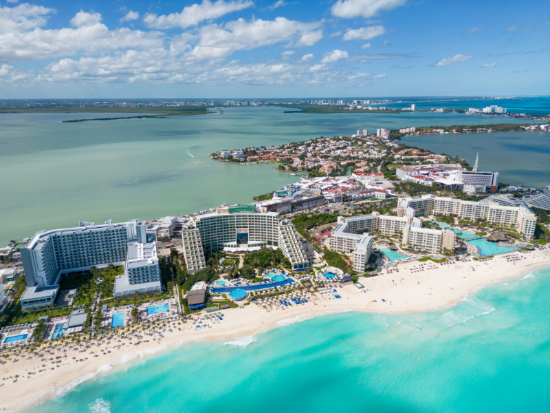 Aerial view of a beachfront resort with turquoise water, white sand beaches, and luxury hotels along the coastline.