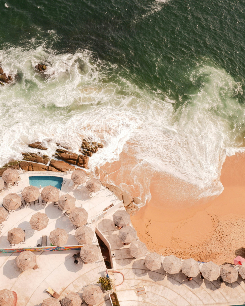 Aerial view of a luxury beachfront resort and ocean waves, a stunning setting for weddings in Mexico.