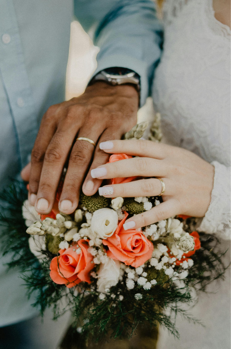 Close-up of bride and groom holding hands over a bouquet during a romantic weddings in Mexico ceremony.