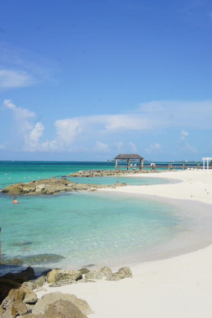 Crystal-clear turquoise water along a white sand beach with rocky shoreline.