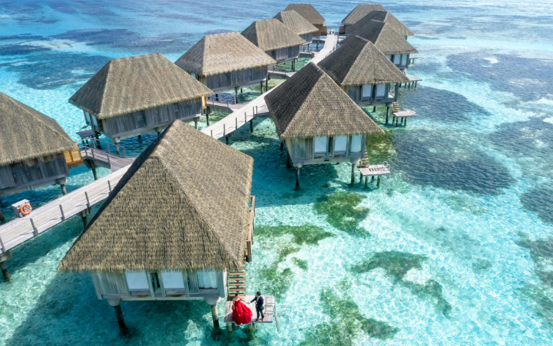 Luxury overwater bungalows surrounded by crystal-clear turquoise water in a tropical island destination.