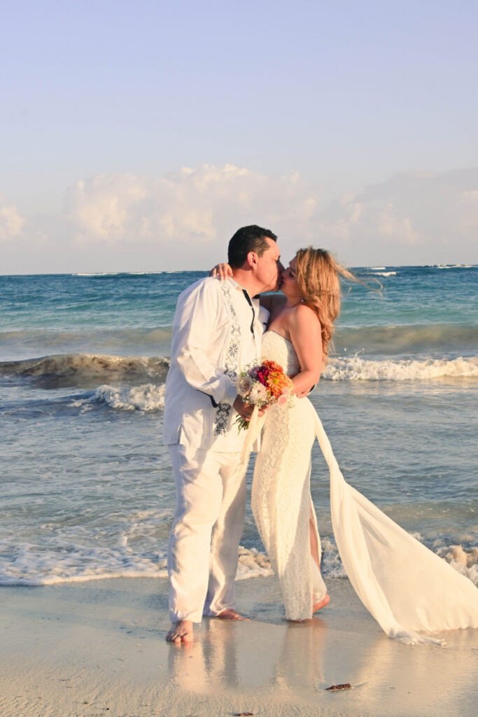 Bride and groom sharing a romantic moment on the beach with ocean waves at sunset