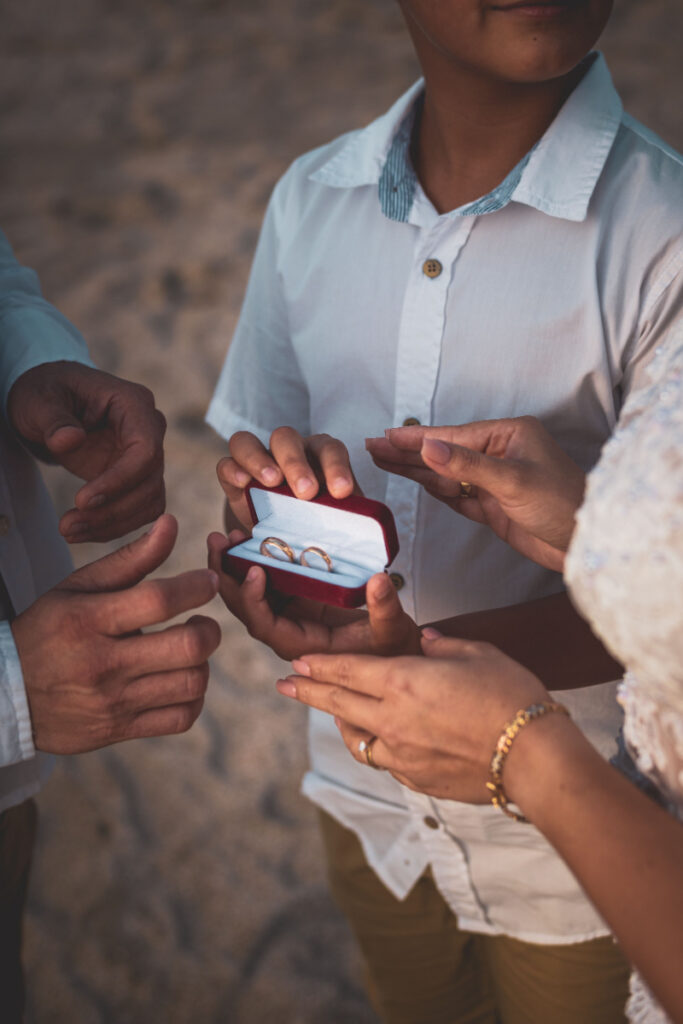 Wedding rings presented during an intimate beach ceremony with loved ones nearby