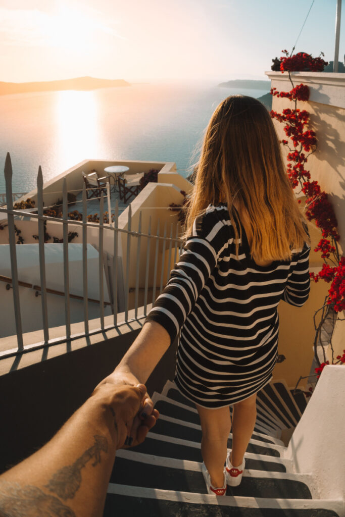 Woman overlooking a seaside terrace at sunset in Santorini, a romantic setting often featured among top honeymoon destinations.